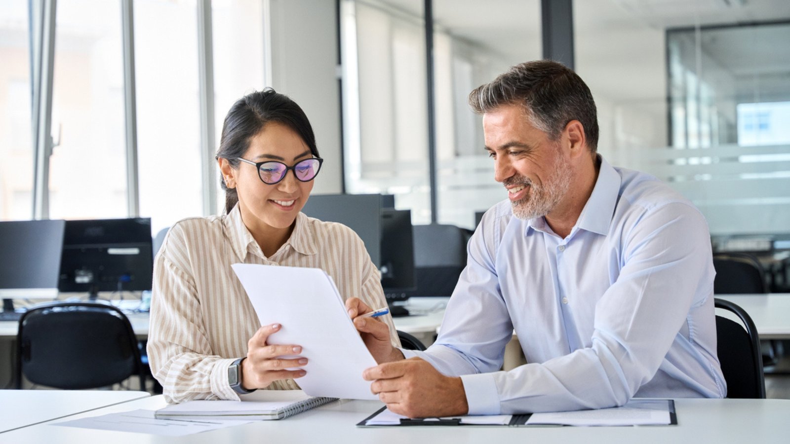 Two colleagues review a document in an office - Bot Group LLC